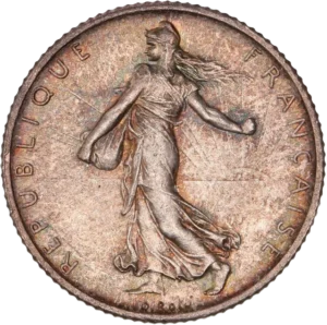 La France sous les traits d'une Semeuse marchant à gauche et semant à contre-vent. Derrière le soleil levant.