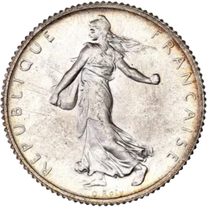 La France sous les traits d'une Semeuse marchant à gauche et semant à contre-vent. Derrière le soleil levant.