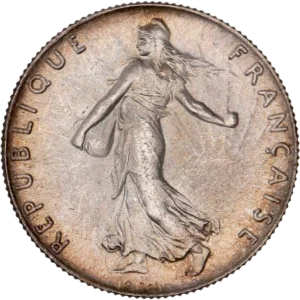 La France sous les traits d'une Semeuse marchant à gauche et semant à contre-vent. Derrière le soleil levant.