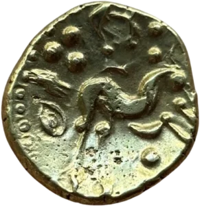 Cheval schématisé, de type belge, à gorge fourchue, galopant à droite. Entre les jambes du cheval, un globule, au-dessus : globule à la pointe de l’oreille, croissant, globules et divers éléments.