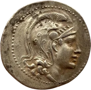 Chouette debout à droite sur une amphore, la tête de face entouré de symbole et d'inscriptions dans une couronne d'olivier.