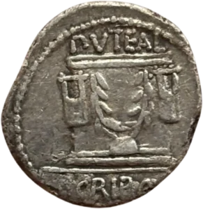 Le puit scribonien (autel) orné de deux lyres et de deux branches de laurier; en bas à gauche, une enclume.