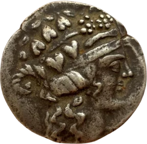 Tête de Dionysos à droite, portant une couronne de feuilles de vigne et de lierre, les cheveux longs.